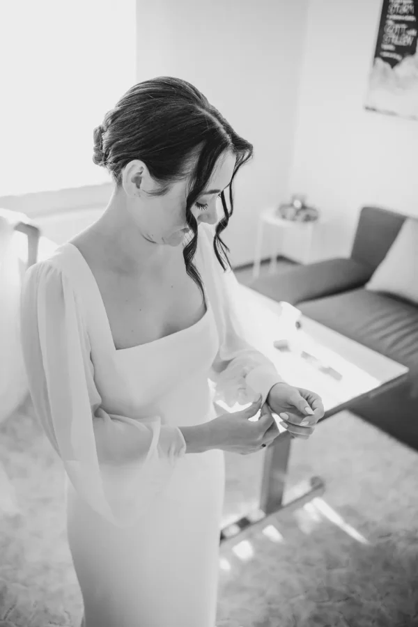 Die Braut knöpft ihr Kleid zu, ein intimer Moment voller Aufregung.