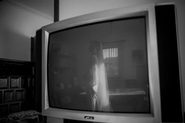 Künstlerische Reflexion der Braut in einem alten Röhrenfernseher, eine stimmungsvolle Aufnahme des Getting Ready.