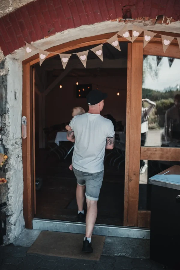 Der Bräutigam betritt die Festscheune mit seiner Tochter auf dem Arm