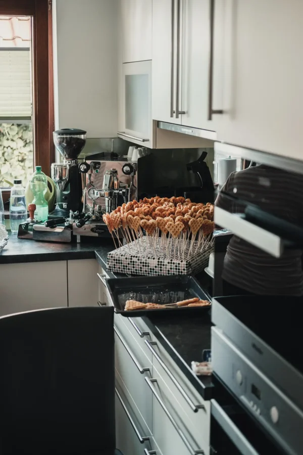 Eine charmante Küche, in der liebevoll vorbereitete Herzwaffeln auf Stäbchen für den Hochzeitstag angerichtet wurden – ein Detail, das die Herzlichkeit und den persönlichen Touch dieser Feier widerspiegelt.