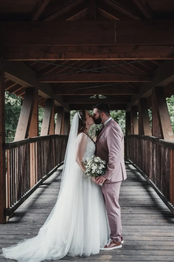 Brautpaar teilt einen innigen Kuss auf der romantischen Holzbrücke