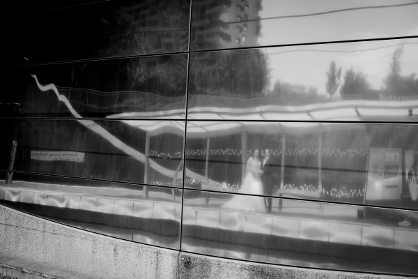 Künstlerische Spiegelung eines Hochzeitspaars in der Glasfassade einer U-Bahn-Station – urbanes Hochzeitsfoto mit einzigartiger Perspektive.