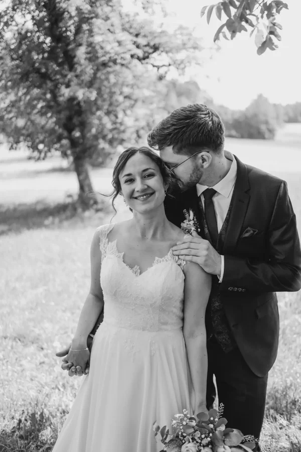 Der Brautppar flüstert der Braut liebe Worte ins Ohr und hält sie an der Schulter fest.