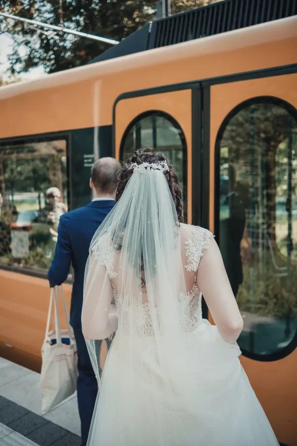 Brautpaar steigt in die U-Bahn ein – stilvolle Kombination aus Hochzeitsromantik und städtischem Flair.
