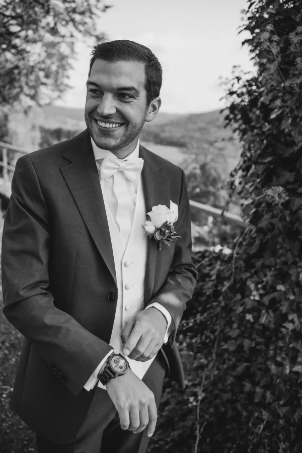 Bräutigam im Anzug, zeigt auf seine elegante Armbanduhr