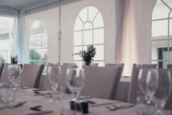 Detailaufnahme einer liebevoll gedeckten Hochzeitstafel im Festzelt mit Blumenarrangement