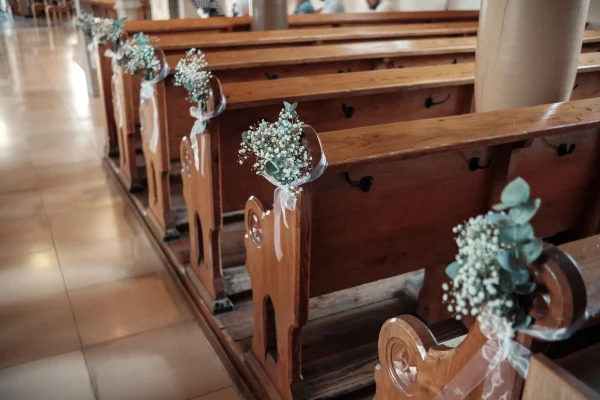 Romantische Hochzeitsdekoration in der Mauritiuskirche Mötzingen – mit zarten Blumenarrangements aus Eukalyptus und Schleierkraut an den Holzbänken.