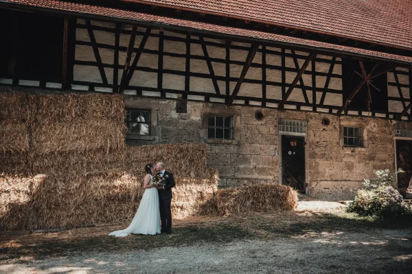 Brautpaar vor der historischen Scheune. Strohballen und Fachwerk