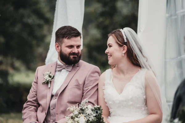 Braut lächelt ihren Bräutigam während des Eheversprechens an