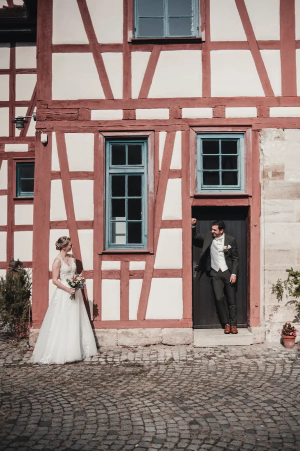 in intimes Paarshooting im Innenhof der Burg Reichenberg. Das Brautpaar posiert vor einer charmanten alten Steinwand, die von grünen Pflanzen umrahmt wird.