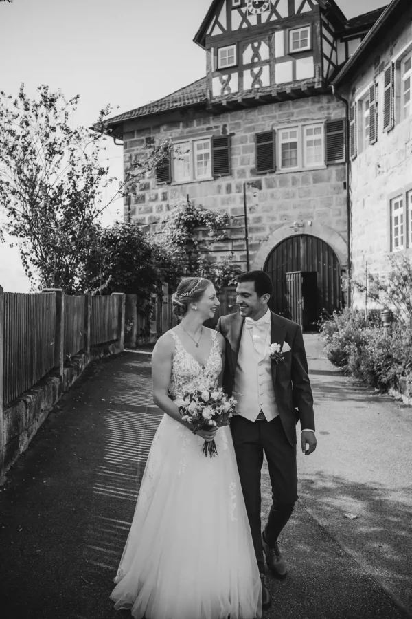 Brautpaar läuft lächelnd vor der Kulisse der Burg Reichenberg
