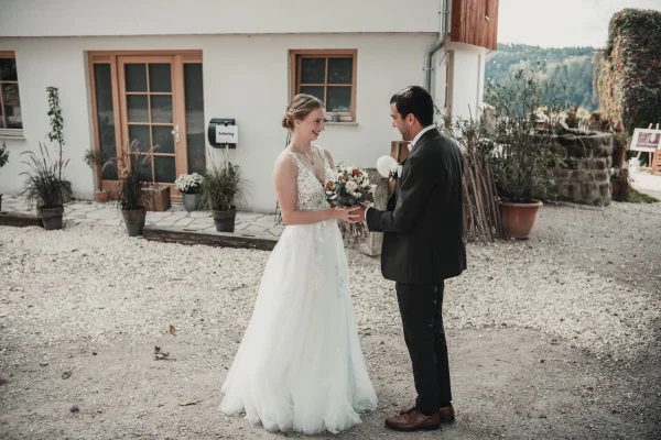 Die Braut tritt mit einem glücklichen Lächeln auf den Hof von Lana Salta, wo sie ihren Bräutigam in einer liebevollen Umarmung begrüßt. Die ländliche Kulisse fügt sich perfekt in den Moment ein.