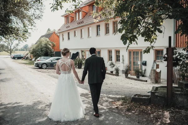 Das Brautpaar geht Hand in Hand auf dem Weg zum Lana Salta, mit einem strahlenden Lächeln und einer entspannten Atmosphäre. Die Aussicht auf das Land unterstreicht den romantischen Moment.
