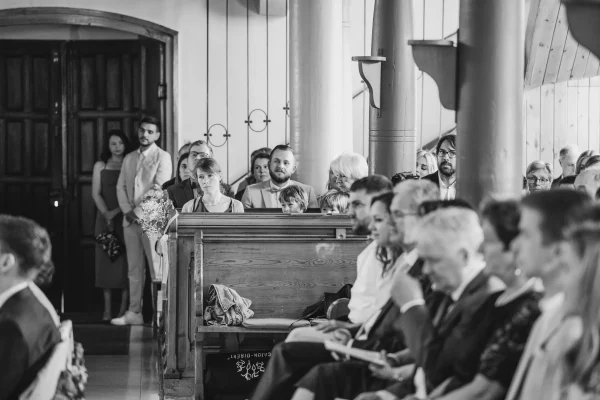 Hochzeitsgäste in der Mauritiuskirche Mötzingen, aufmerksam den Trauungsworten lauschend, mit emotionalen und erwartungsvollen Blicken.