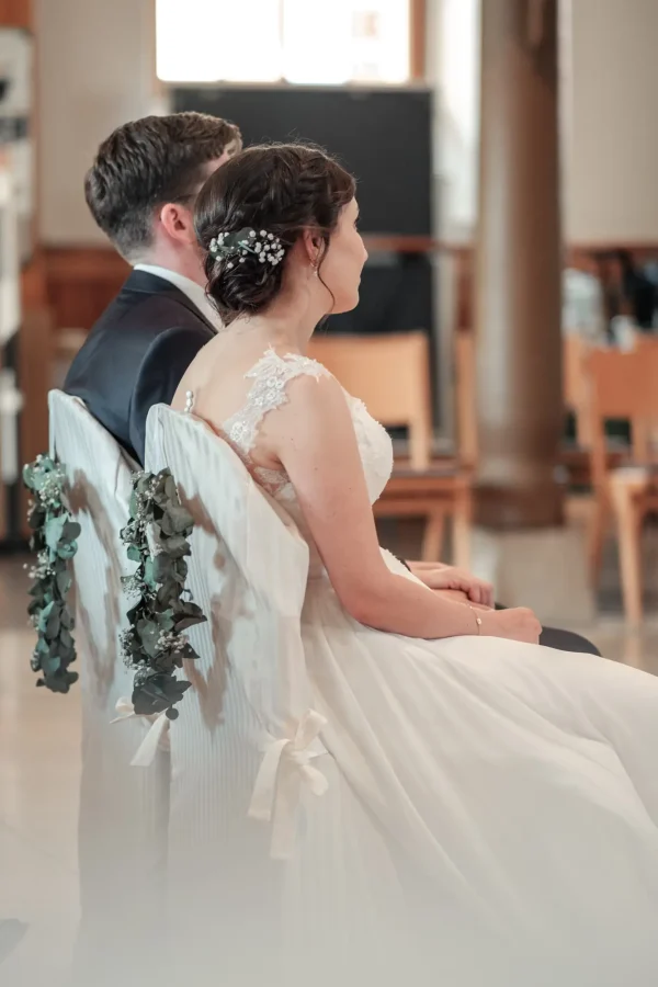 Ena & Daniel sitzen während der Trauung in der Mauritiuskirche Mötzingen auf festlich geschmückten Stühlen mit Eukalyptusgirlanden.
