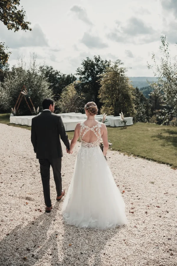 Das Brautpaar geht Hand in Hand durch die weite Landschaft von Lana Salta. Der idyllische Hintergrund und das natürliche Licht unterstreichen die friedliche Atmosphäre des Moments.