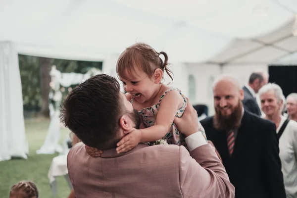 Der Bräutigam wird herzlich von einem Kind umarmt und beglückwünscht