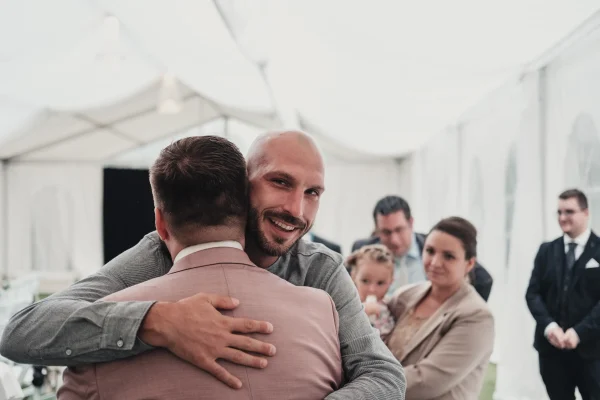 Der Bräutigam wird herzlich von einem Freund umarmt und beglückwünscht