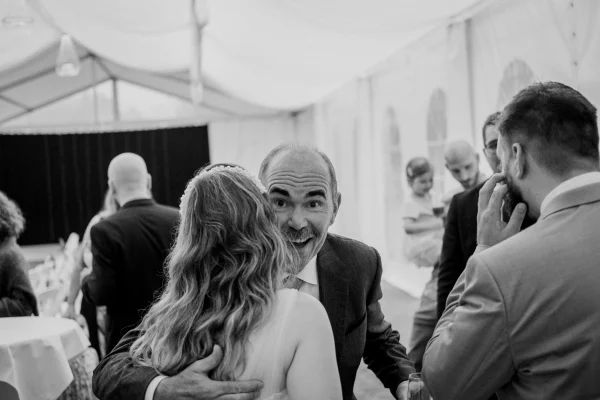 Ein lachender Gast gratuliert der Braut zur Hochzeit