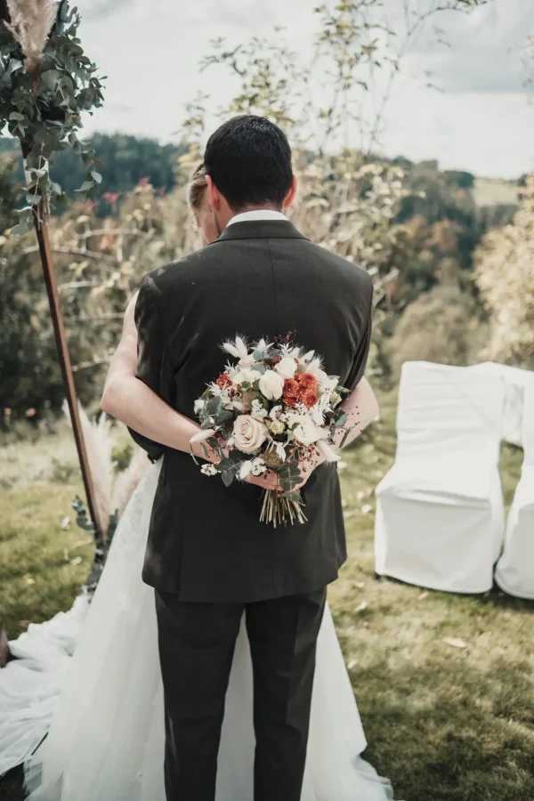 Das Brautpaar steht vor einem wunderschön dekorierten Traubogen aus Holz und Pampasgras, eingebettet in die grüne Natur von Lana Salta – ein wahrhaft traumhafter Hintergrund für ihre Hochzeit.