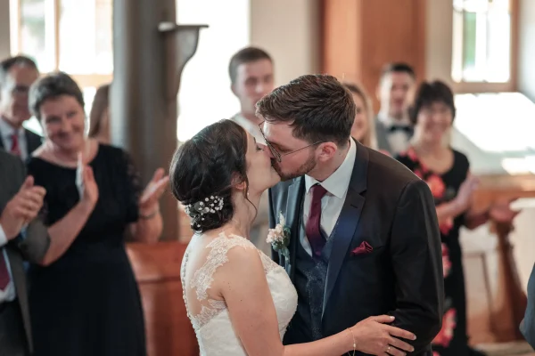 Der Hochzeitskuss: Ena & Daniel küssen sich nach der Eheschließung, während die Gäste in der Mauritiuskirche Mötzingen applaudieren.