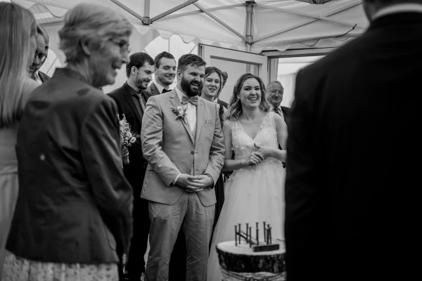 Das Brautpaar lacht gemeinsam mit den Gästen beim Sektempfang