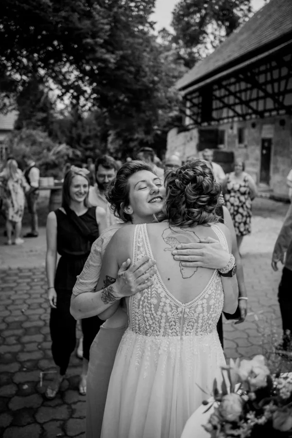 Gäste gratulieren dem Brautpaar herzlich, Umarmungen und Glückwünsche in festlicher Umgebung.