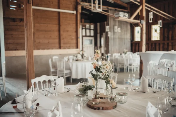 Liebevoll gedeckte Hochzeitstafel in der rustikalen Eventlocation Lindenhof Mötzingen. Elegante Blumendekoration, Holzdetails und hängende Laternen verleihen dem Saal eine romantische Atmosphäre.