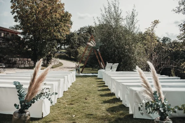 Der wunderschön dekorierte Außenbereich des Lana Salta mit weißen Stühlen und einem rustikalen Traubogen, perfekt für die freie Trauung.