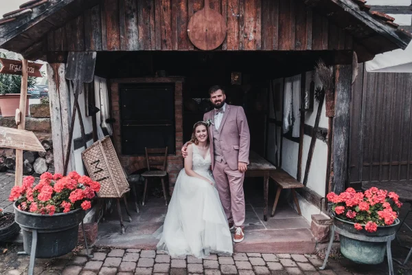 Das Brautpaar posiert vor einer rustikalen Holzhütte für ein romantisches Shooting
