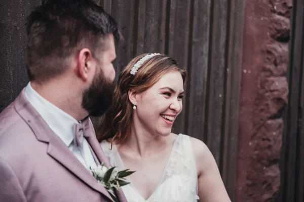 Die Braut lacht glücklich, während der Bräutigam sie sanft anlächelt