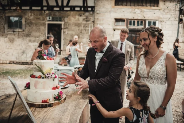 Der Bräutigam und ein Kind bestaunen die dreistöckige Torte. Der Bräutigam macht eine Grimasse.