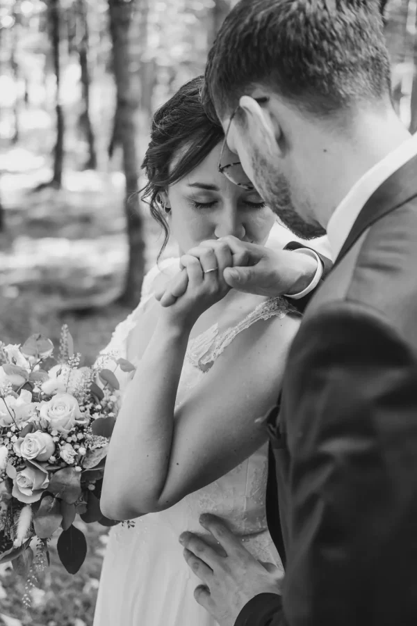 Die Frau küsst den Ehering ihres Mannes. Schwarz-weiß Aufnahme.