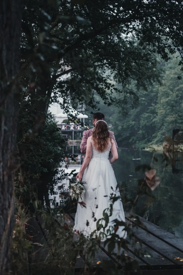 Braut und Bräutigam tanzen auf einer grünen Wiese bei Abenddämmerung