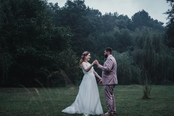 Braut und Bräutigam tanzen auf einer grünen Wiese bei Abenddämmerung