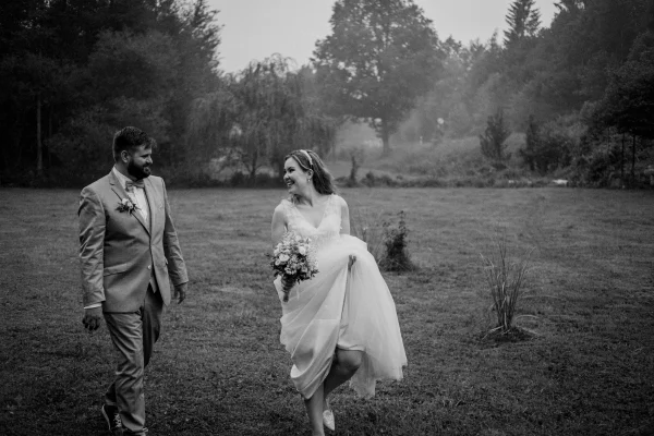 Schwarz-weiß Bild von Braut und Bräutigam lachend auf einer Wiese