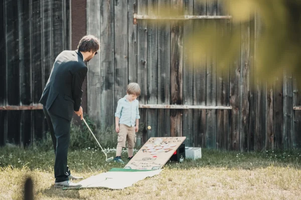 Hochzeitsgäste am Nachmittag. Minigolf spielend vor einer Scheune des Lindenhofs.