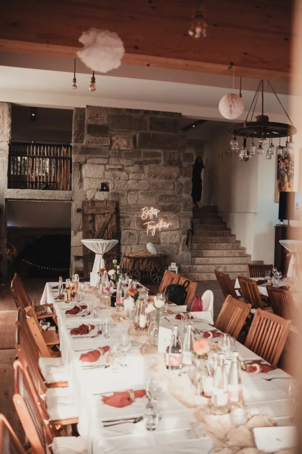 Blick ins Innere des Lana Salta, Tische mit Dekoration, Holzbalken und Steinwand im Landhausstil