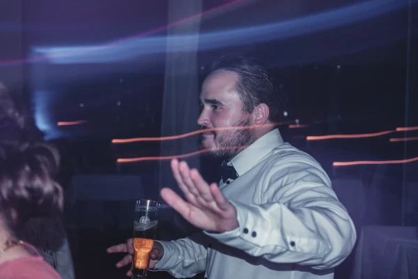 Tanzender Gast mit Lichtspielen und Bierglas in der Hand