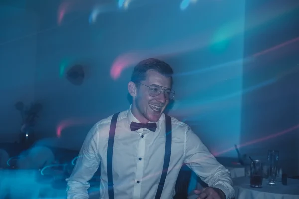 Lachender Hochzeitsgast mit Hosenträgern und Fliege.