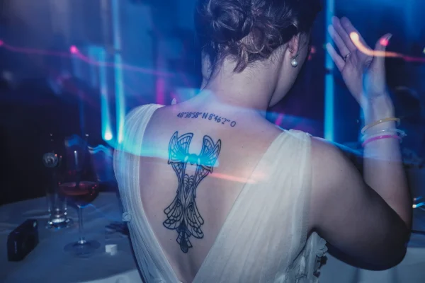 Braut tanzt mit leuchtenden Armbändern unter buntem Licht.