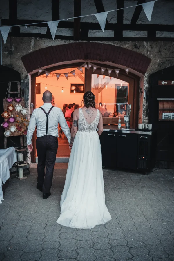 Das Brautpaar betritt die warm beleuchtete Festscheune nach dem Shooting.