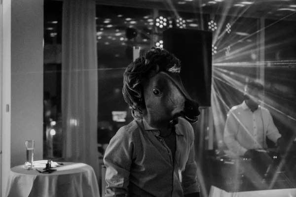 Schwarz-Weiß-Bild mit einer Person in einer Pferdemaske auf der Tanzfläche.