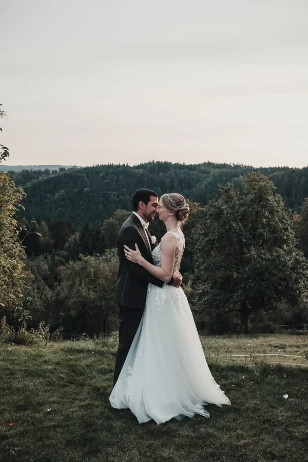 Brautpaar in liebevoller Umarmung kurz vor dem Kuss auf der Terrasse am Abend