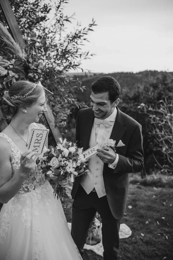 Schwarz Weiß Aufnahme von Braut und Bräutigam, lächelnd mit Mr. und Mrs. Schildern.