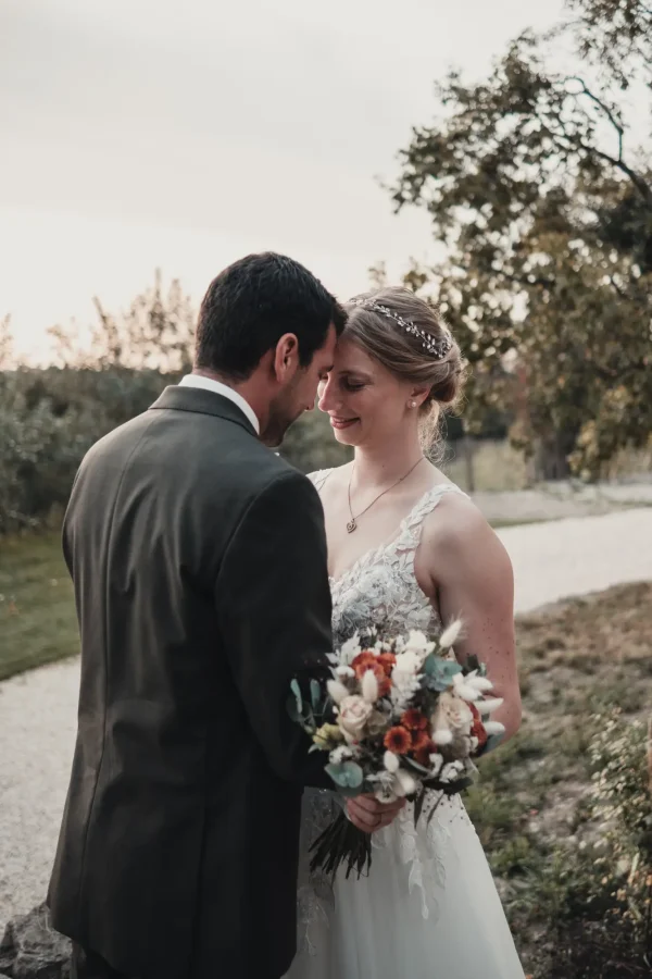 Der Bräutigam blickt der Braut tief in die Augen. Abendstimmung mit Brautstrauß.