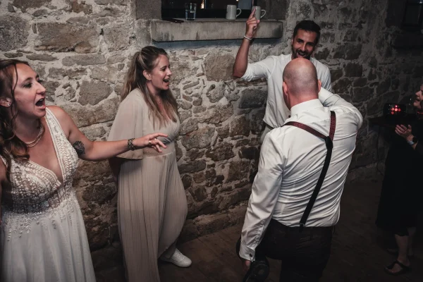 Die Hochzeitsgesellschaft feiert ausgelassen, lachende Gäste und fröhliche Stimmung auf der Tanzfläche.