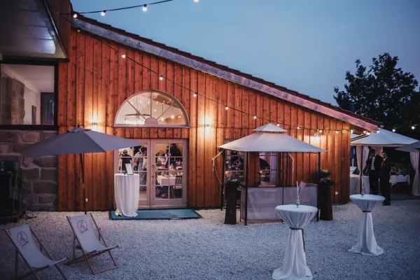 Außenansicht des Lana Salta. Rustikale Holzwand und festliche Beleuchtung am Abend.